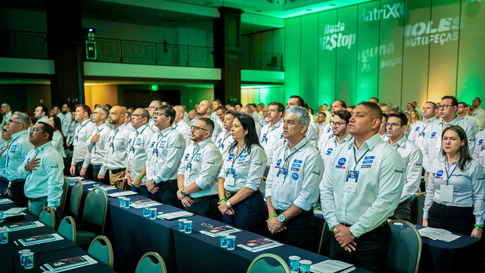 Participantes em pé com iluminação verde no salão da convenção