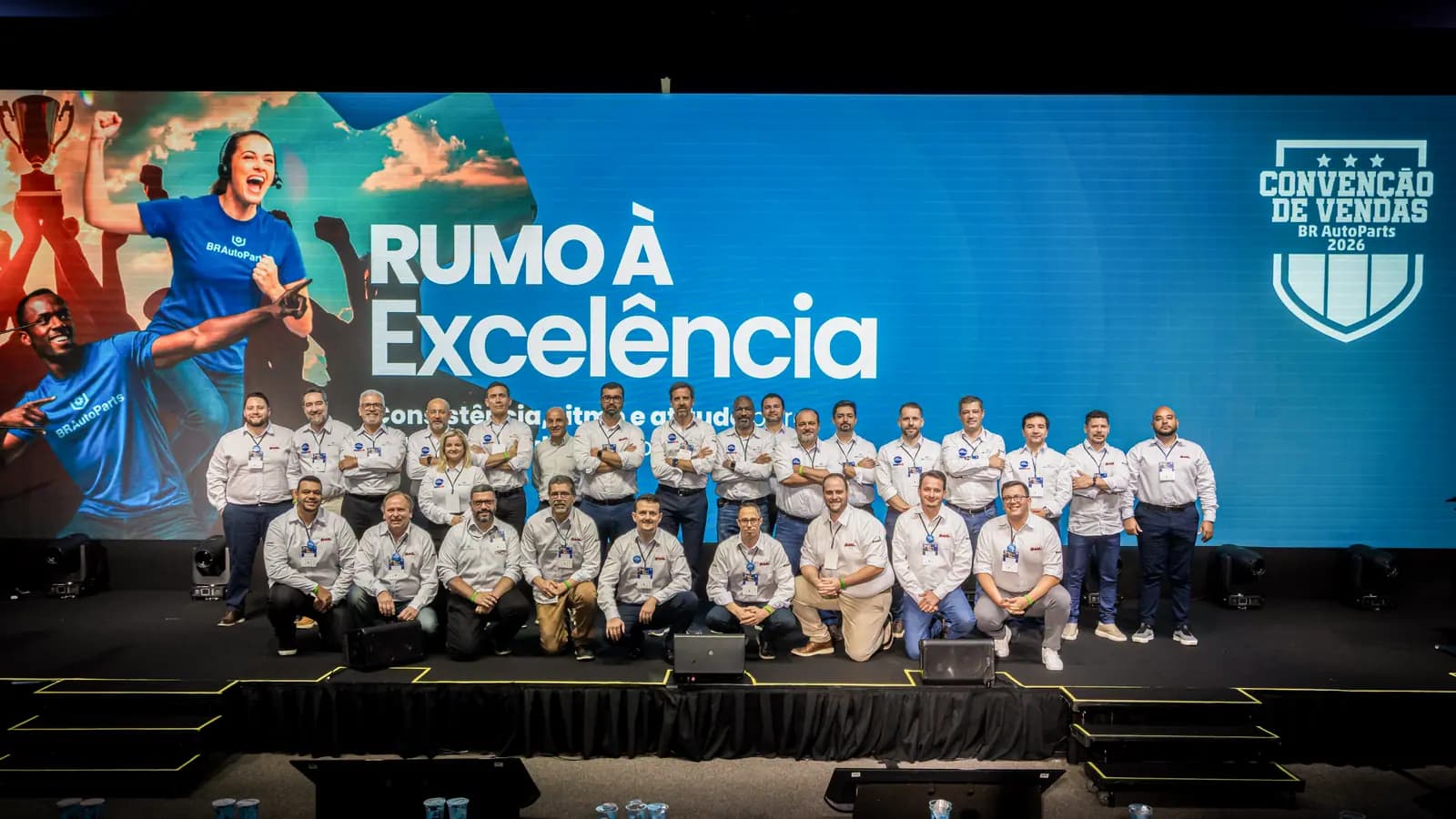 Equipe reunida no palco diante do telão da convenção