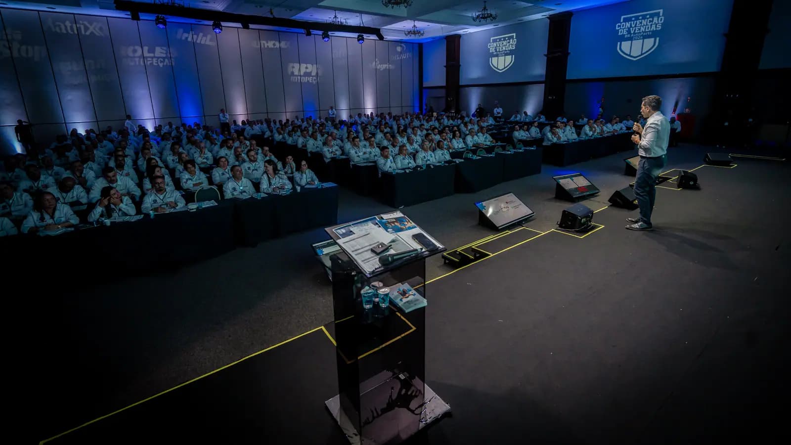 Palestrante no palco com a plateia ao fundo