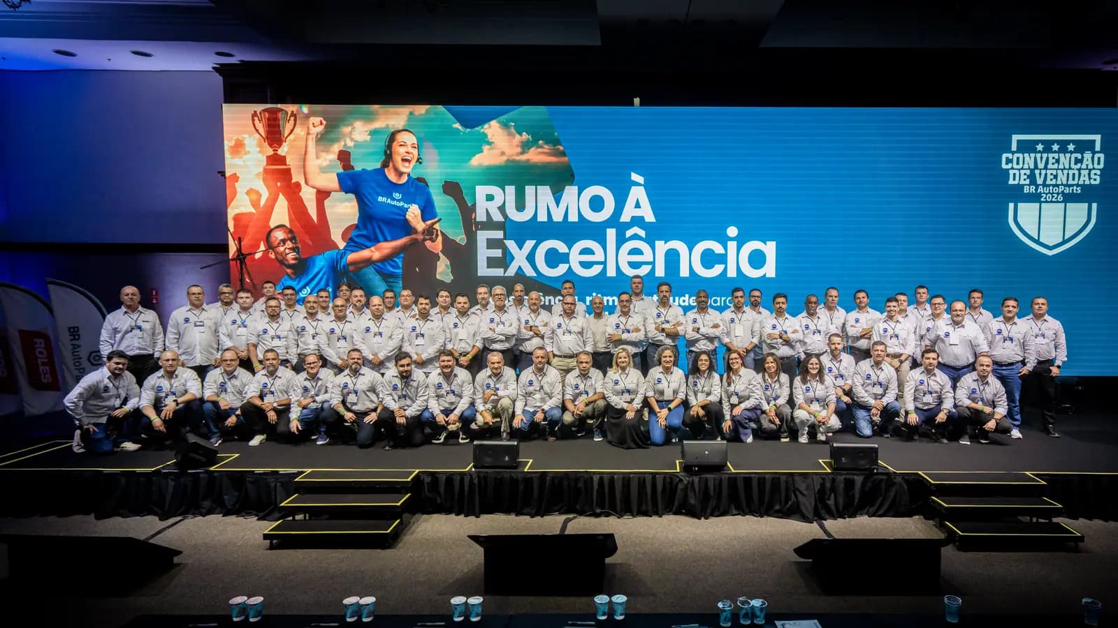 Foto oficial da equipe reunida no palco da convenção de vendas
