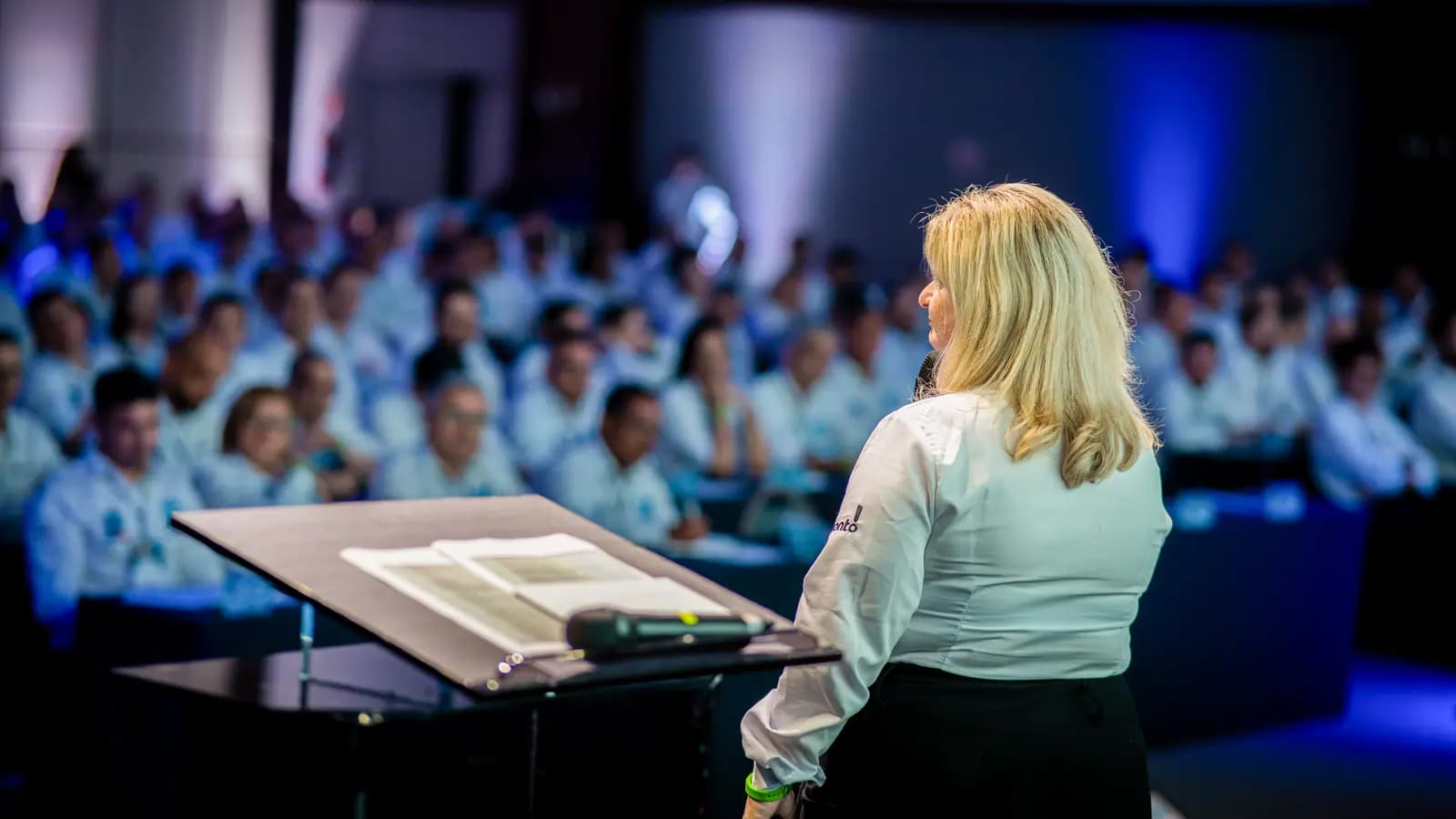 Apresentadora no púlpito conduzindo a convenção de vendas
